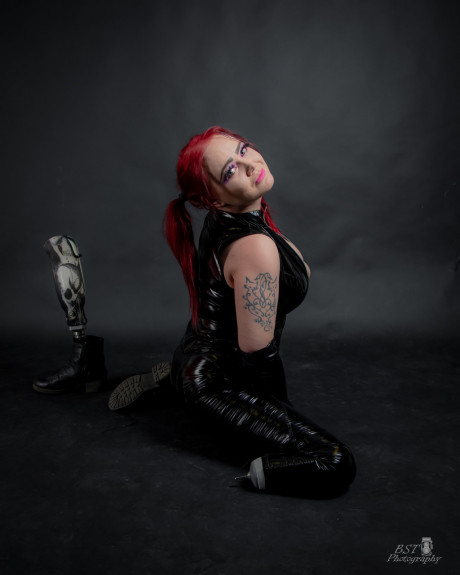 Redheaded tattooed only fans model Amputee Sofia poses in a latex outfit