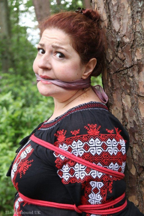 Chunky redhead is cleave gagged and tied to a tree in a forest - #812601