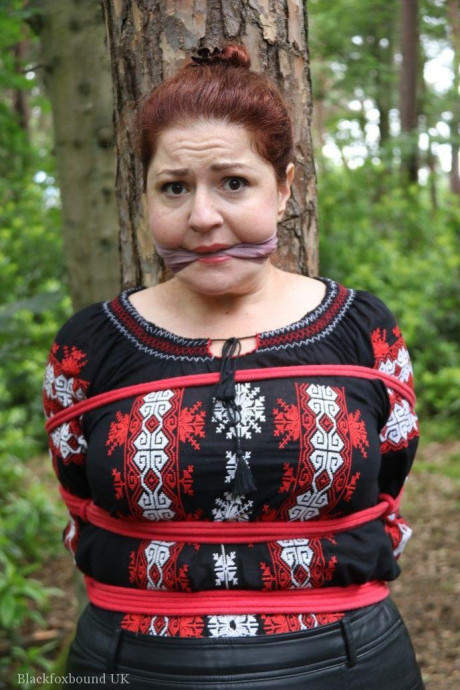 Chunky redhead is cleave gagged and tied to a tree in a forest - #812603