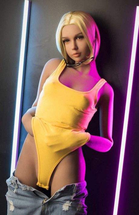 Yellow-haired sex doll Mirta poses fully clothed and shows her slender undressed body