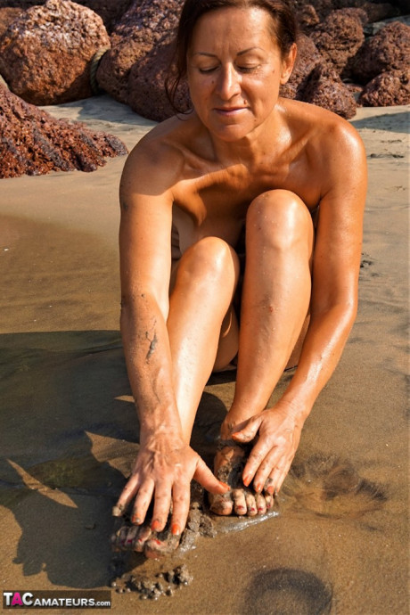 Naked cougar girl Diana Ananta covers her feet in beach sand at low tide - #1145667