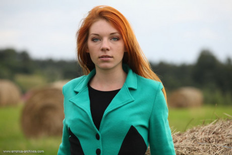 Redheaded young Amber A gets totally nude against a round bale in a field - #869927