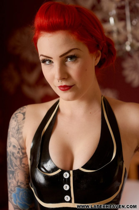 Tattooed ginger poses in black latex clothing and high heels in a bedroom - #1138014