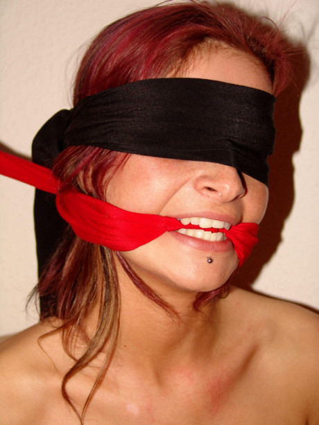 Restrained ginger head struggles against her bindings while blindfolded and gagged