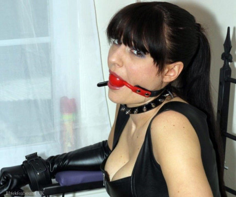 Solo woman sports a ball gag while tied to a seat in leather clothes - #458281