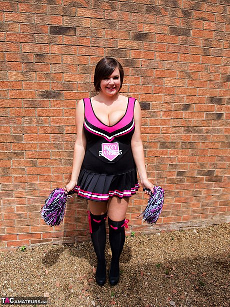 Chubby cheerleader Roxy uncovers her massive melons against a brick wall - Image 1 of 16  in Amateur category   featuring Roxy Anderson 