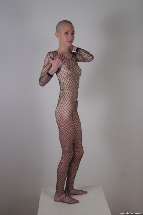 Solo model with a shaved head poses in a fishnet bodystocking - #40206