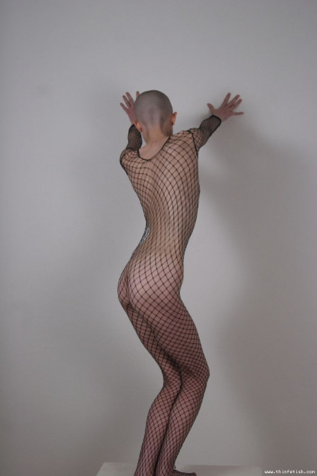 Solo model with a shaved head poses in a fishnet bodystocking - #40209