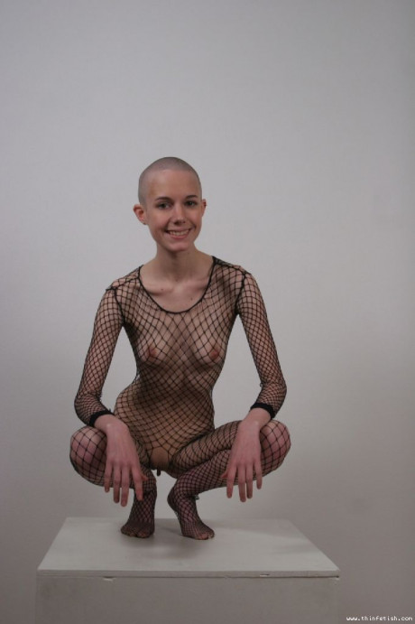 Solo model with a shaved head poses in a fishnet bodystocking - #40211