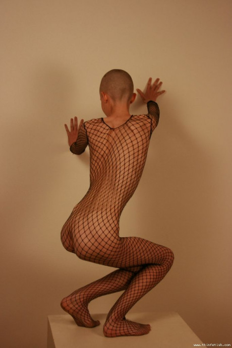 Solo model with a shaved head poses in a fishnet bodystocking - #40217