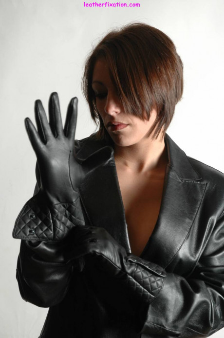 Fully clothed female pulls on a pair of black leather gloves - #1238486