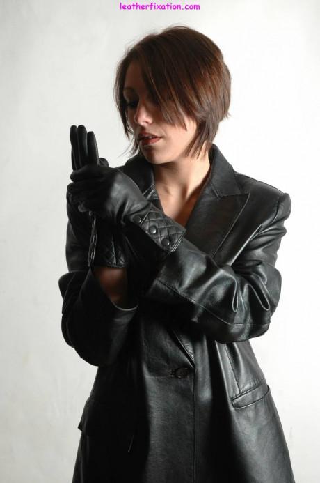 Fully clothed female pulls on a pair of black leather gloves - #1238490