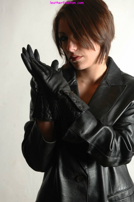 Fully clothed female pulls on a pair of black leather gloves - #1238491