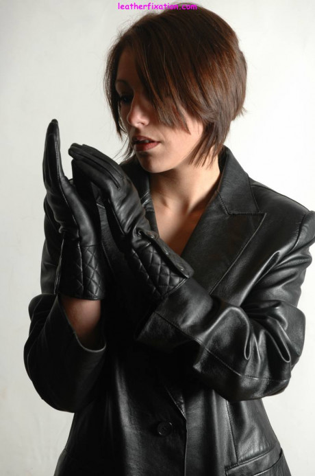 Fully clothed female pulls on a pair of black leather gloves - #1238493