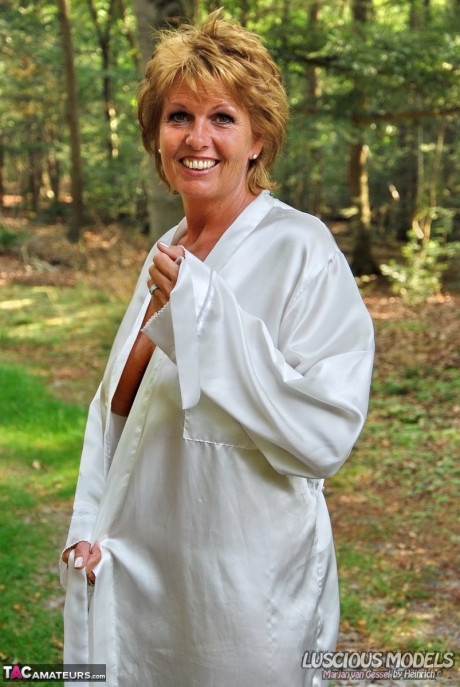 Mature ginger head removes a robe to stand naked in red heels while in the woods - #1087755
