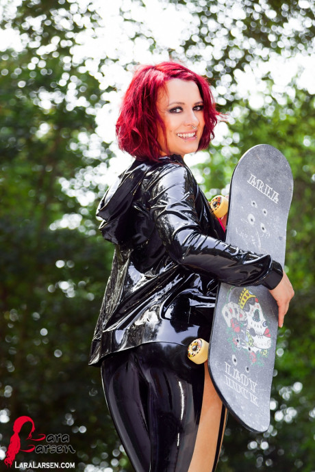 Redheaded model Lara Larsen unzips her latex clothing at a skate park - #383296