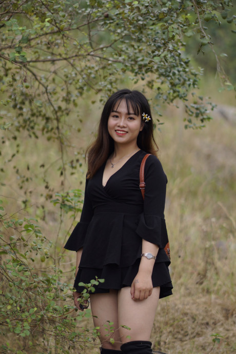 Pretty asian babe posing in her black dress and boots in nature