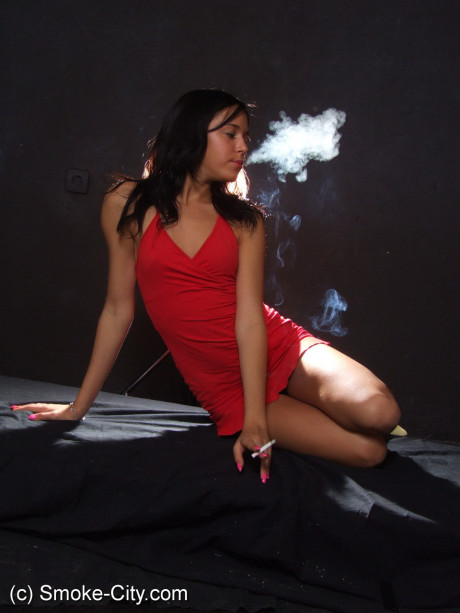 Young teenie brunette shows her sleek legs while smoking in a red dress - #187329