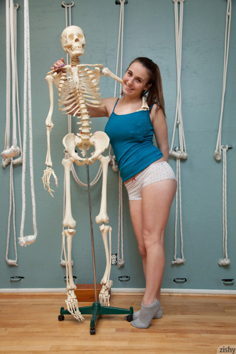 Playful young Nina Gitch poses braless in charming top & panties next to a skeleton - #74640