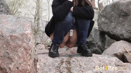 Brunette girl chick Lara Fox pulls down her jeans to take a piss upon boulders