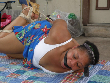 Mature black plumper is hogtied on a comforter while cleave gagged