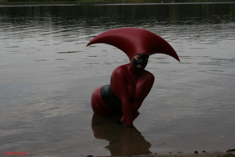 Fetish model Avengelique wades into a body of water in a rubber costume - #305541
